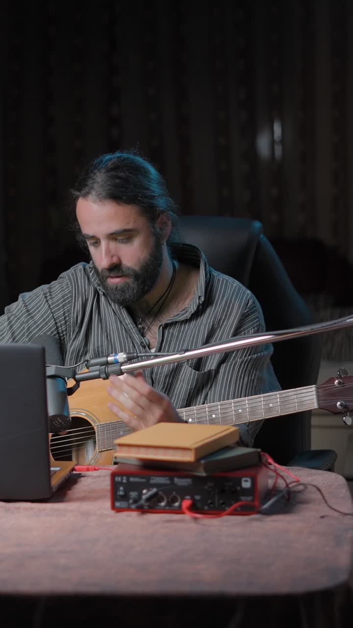 Man setting up acoustic guitar and audio equipment for music recording