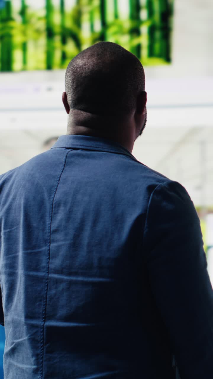 Man Standing and Observing Digital Screens in Modern Office