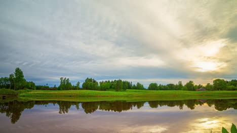 Timelapse-of-clouds-passing-over-a-pond-and-ripples-in-the-water-at-sunset