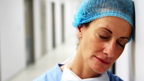 sad surgeon leaning on wall in corridor