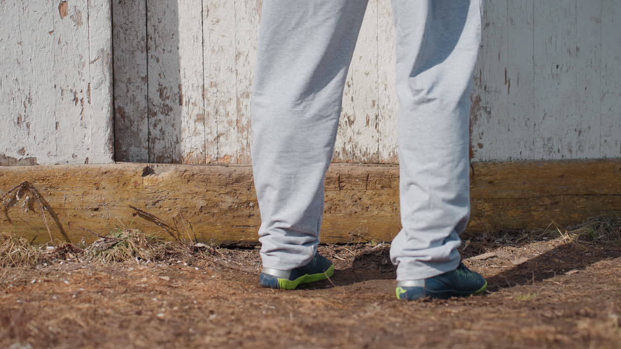 Pausas individuales antes de la entrada a una puerta histórica; una persona duda momentáneamente junto a la puerta de entrada antigua; una persona permanece inmóvil por un momento en el umbral de la entrada antigua, en señal de duda.