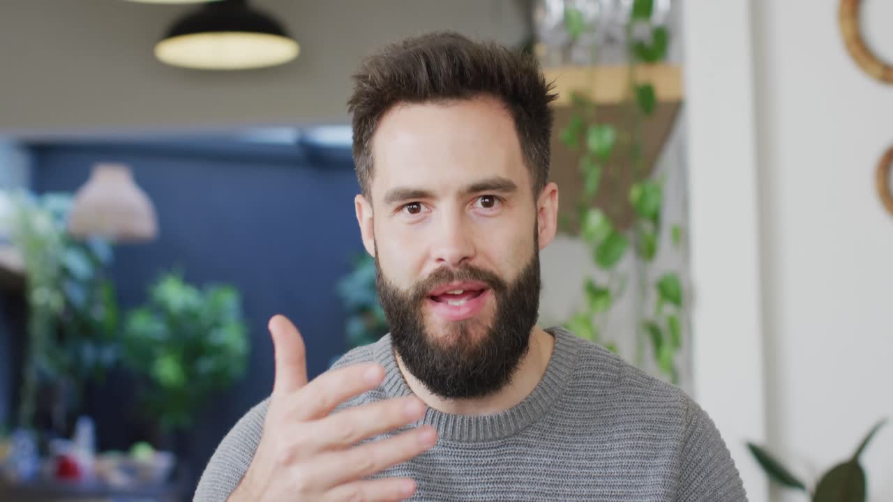 video de un hombre caucásico feliz y barbudo hablando y gesticulando, haciendo una videollamada en casa, copia el espacio