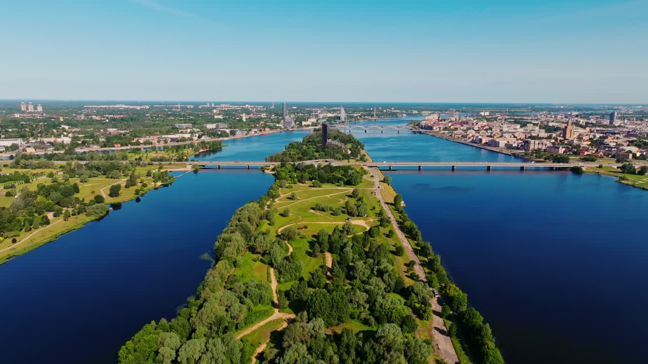 Drone flies forward across Zaķusala island showing Daugava river and cityscape