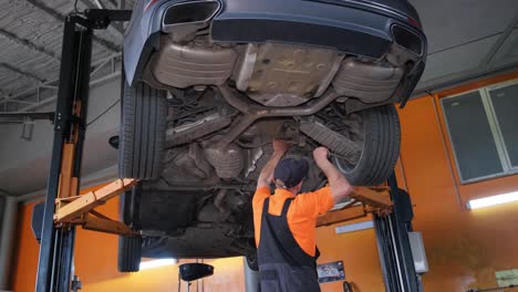 mechanic working on the underside of a car in a garage