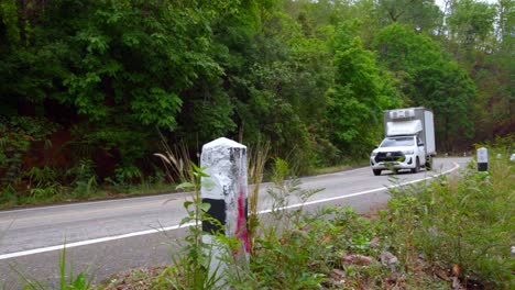 Toma-De-Una-Camioneta-Blanca-Que-Pasa-Por-Un-Camino-Sinuoso-A-Lo-Largo-Del-Terreno-Montañoso-En-El-Norte-De-Tailandia-Durante-El-Día