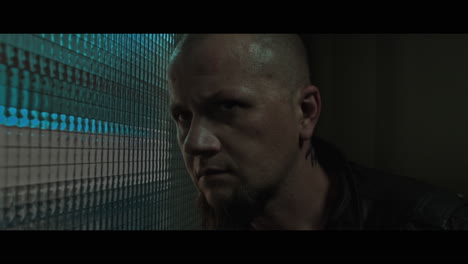 a bald dangerous looking man checks the corridor through reinforced glass