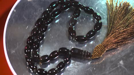 Black-pincer-beads-rosary-turntable-display-slow-motion-black-gems-stones-top-down-view