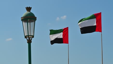 imágenes de 4k: dos banderas nacionales de emiratos árabes unidos ondeando en el viento contra el cielo azul claro, una parte de las celebraciones del día nacional de los emiratos árabes unidos