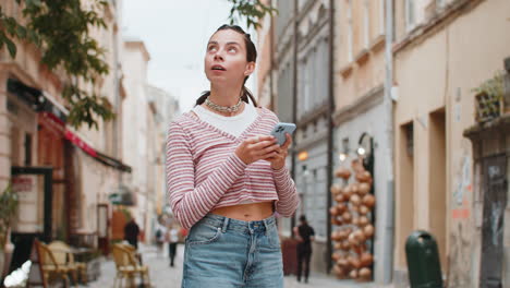 tourist traveler young woman using smartphone search a way on map in navigator app on city street