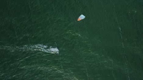 Establishing-aerial-view-of-a-group-of-people-engaged-in-kitesurfing,-sunny-summer-day,-high-waves,-extreme-sport,-Baltic-Sea-Karosta-beach-,-birdseye-drone-dolly-shot-moving-right