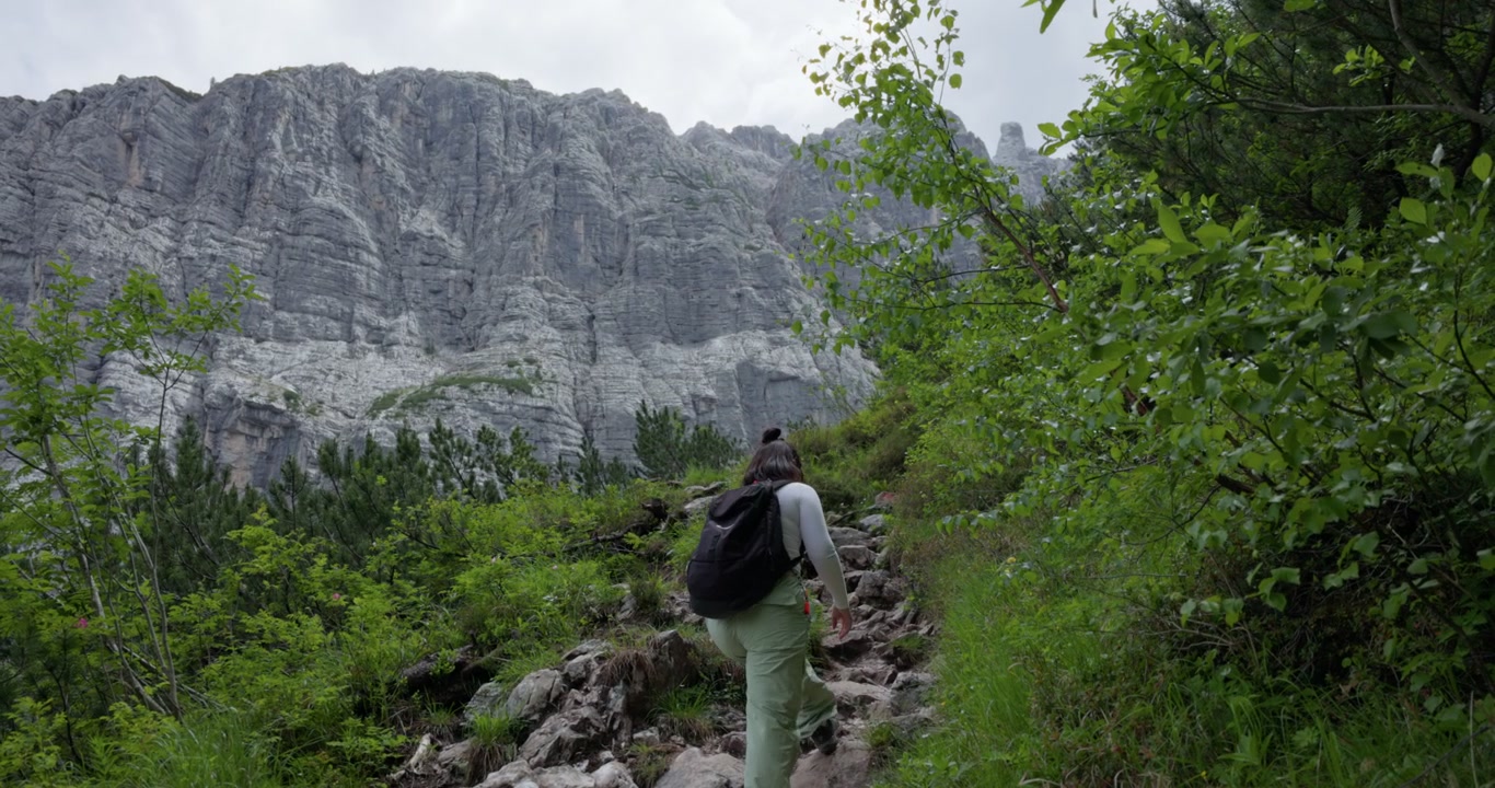Una donna escursionista che cammina lungo un sentiero vicino al Lago di Sorapis nelle Dolomiti, Veneto, Italia - inquadratura ampia.