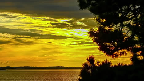 Puesta-De-Sol-Sobre-El-Lago-Cerca-De-La-Orilla-En-Timelapse-Con-Movimiento-De-Nubes-Oscuras-Sobre-El-Cielo-Amarillo