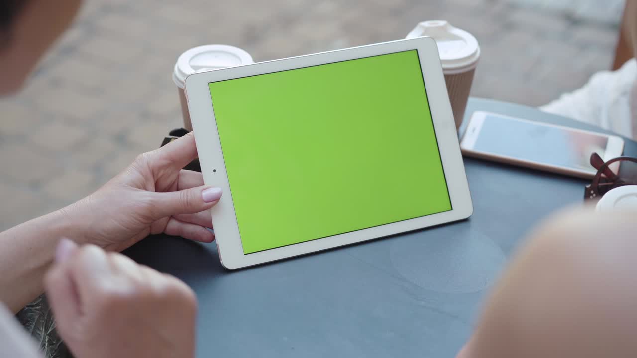 세 명의 인식 할 수없는 여성이 태블릿에서 크로마키 화면을 스크롤합니다. 중년 백인 여성이 인터넷을 서핑하거나 야외 카페에 앉아 온라인 쇼핑합니다. 현대 라이프 스타일의 무선 기술.