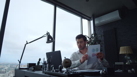 Focused-businessman-looking-at-graphics-on-document-in-office