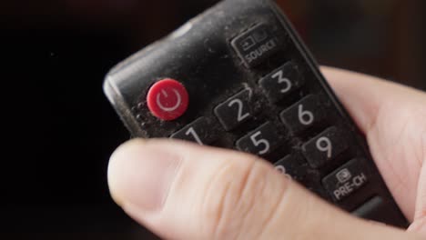 tv sosteniendo el control remoto y presionando el botón rojo de encendido y apagado con el pulgar, cerrar
