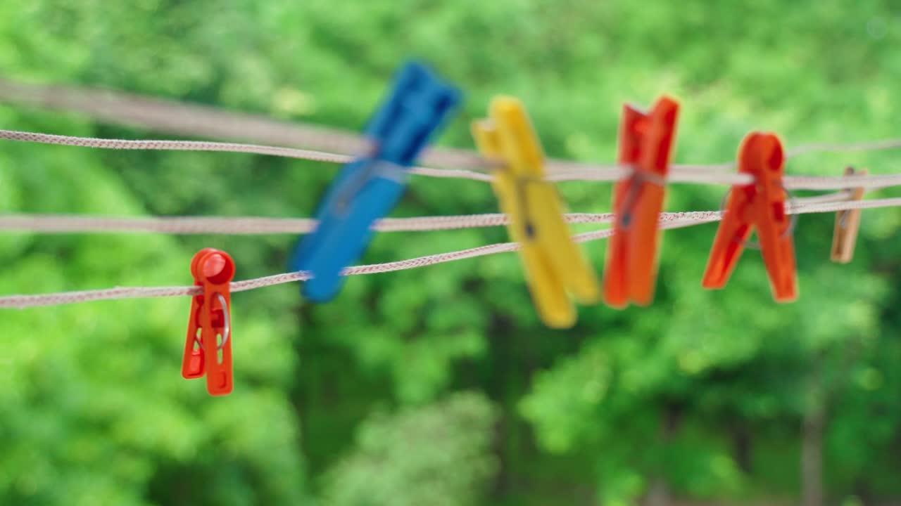 Multi-colored clothespins sway in the wind on the clothesline.