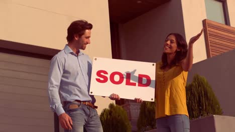 una pareja hispana sonriente frente a su nueva casa.