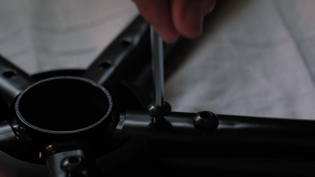 Tomada estática em close-up do uso de chave Allen para apertar a base de uma cadeira gamer durante a montagem de móveis internos e configuração DIY.