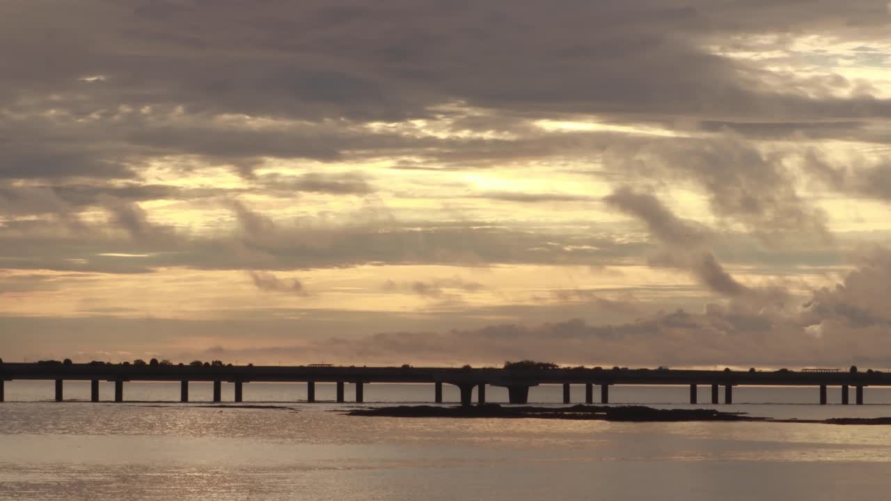 un espectacular amanecer matutino con vistas al canal de panamá y al lejano puente de la cinta costera, el sol matutino iluminando las pesadas nubes de lluvia tropical con hermosos colores dorados, ciudad de panamá