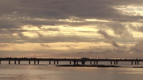 a dramatic morning sunrise overlooking the panama canal and the distant cinta costera bridge, the morning sun illuminating the heavy tropical rain clouds with beautiful golden colours, panama city