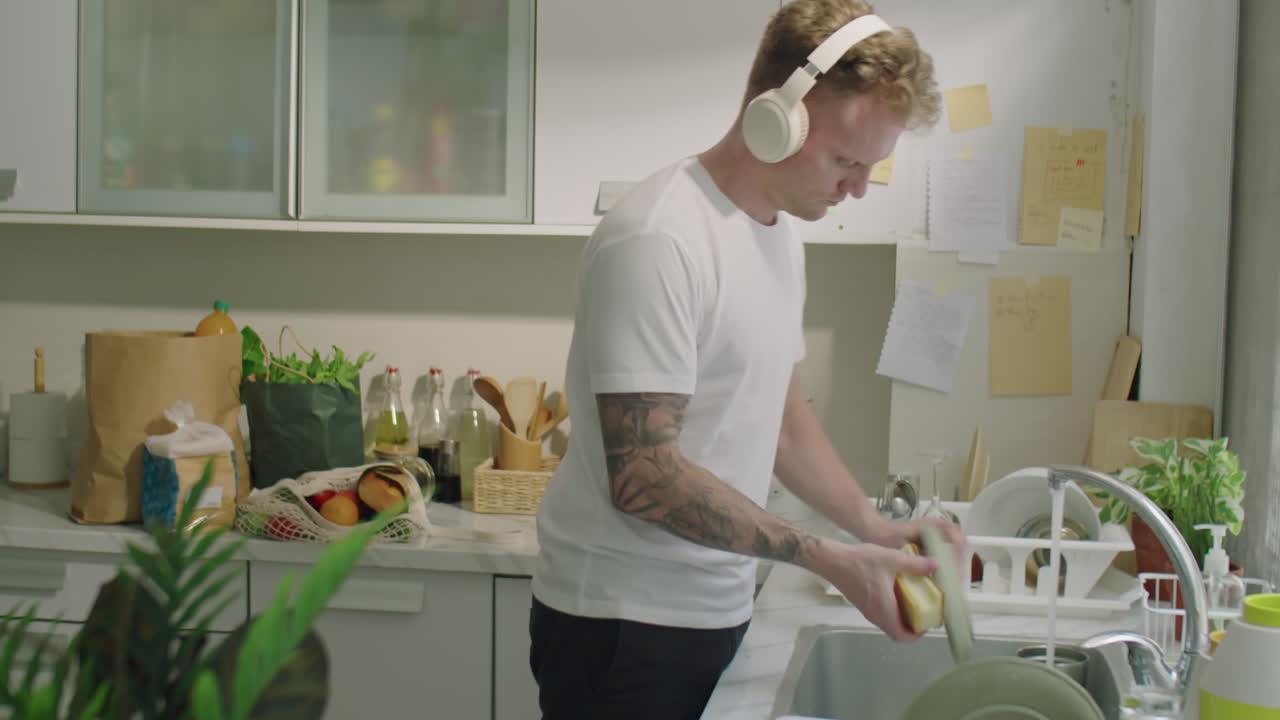 Man in Headphones Doing Dishes in Kitchen