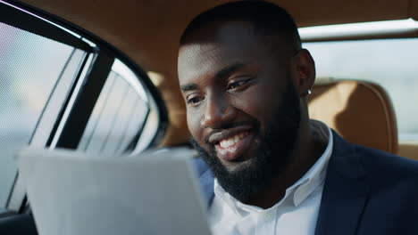 joyful african business man reading documents at car