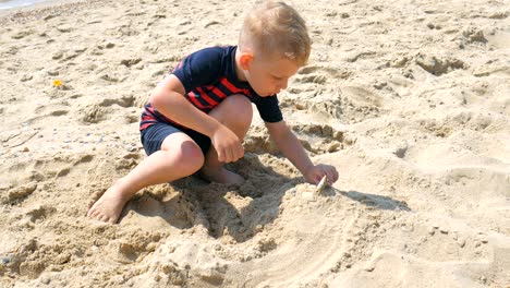 boy having fun playing with toys and building sandcastles on beach.