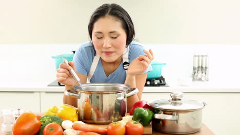 happy woman stirring pot and smiling at camera