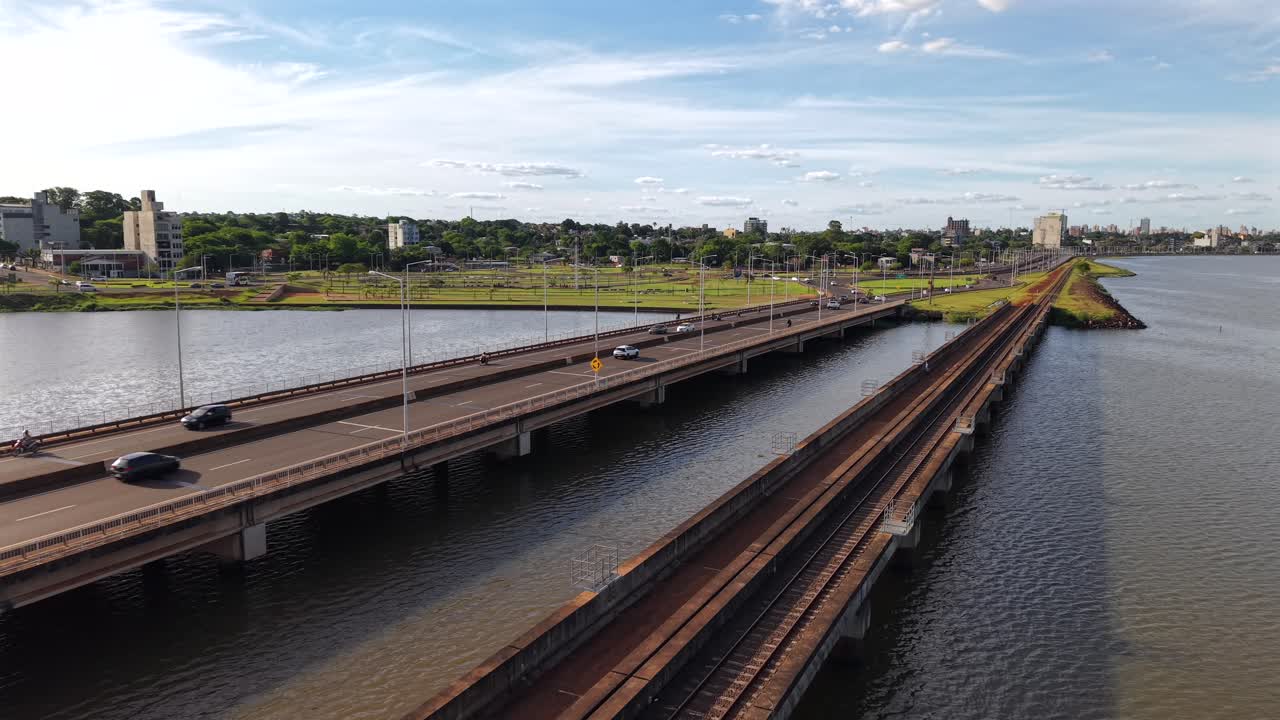 Aerial tracking shot of highway and railway lines crossing the Paraná River, modern city buildings of southern access to Posadas, Argentina