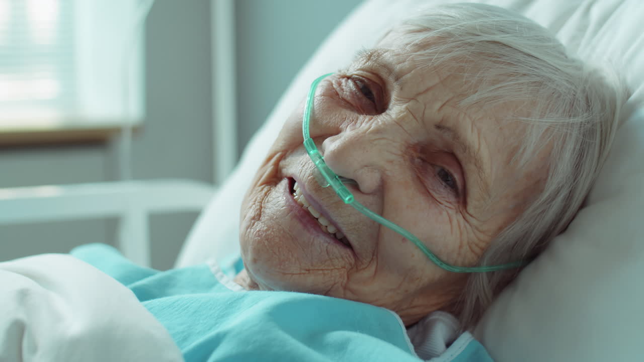 retrato de una mujer mayor sonriente con una cánula nasal en el hospital