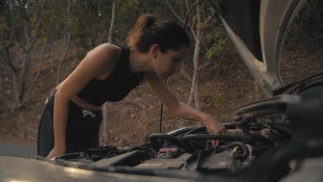 una mujer arreglando un coche averiado.