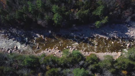 Bird's-eye-view-of-dried-swift-river-full-of-rocks-in-White-Mountains,-USA