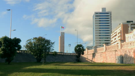 Torre-Del-Reloj-En-Figueira-Da-Foz,-Y-El-Edificio-Del-Gran-Hotel,-En-El-Fondo-El-Cielo-Azul-Con-Nubes