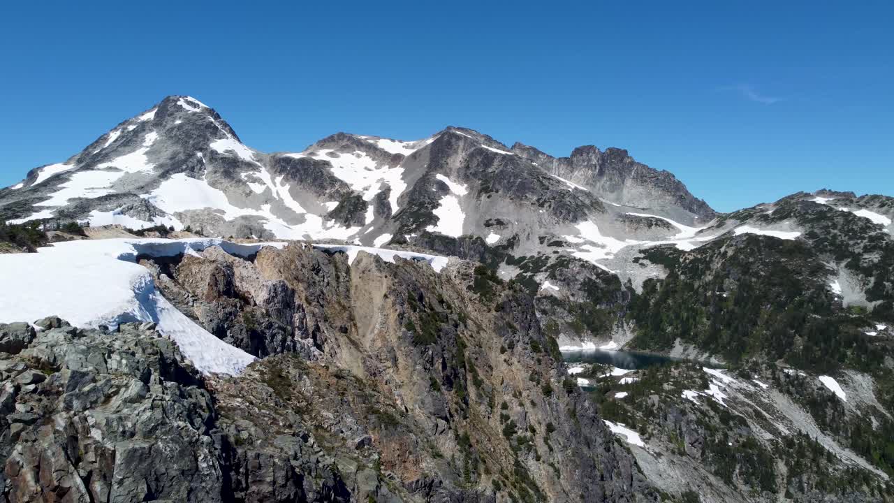 Paesaggio in cima a una montagna con ripresa panoramica con drone aereo, con neve, pini e un cielo blu brillante