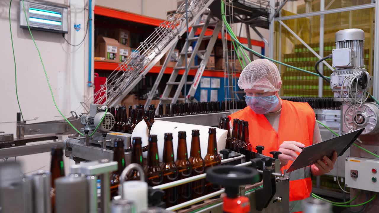 Trabajador de fábrica inspeccionando botellas de cerveza en la línea de producción
