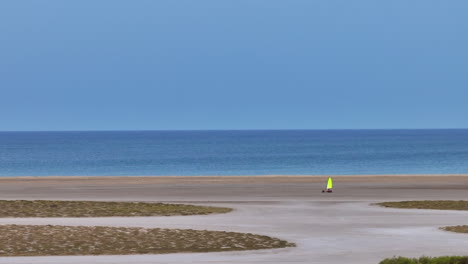 a person sailing on a sandy beach with blue sky and ocean in the background