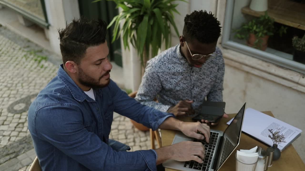 야외 카페에서 디지털 장치를 사용하는 다민족 프리랜서