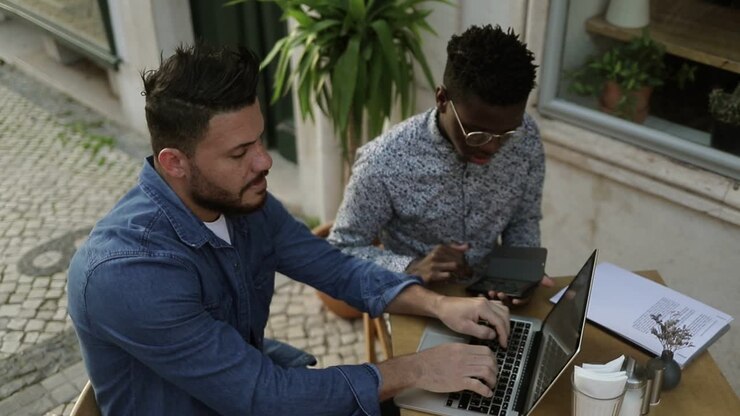 Multiethnic freelancers using digital devices in outdoor cafe