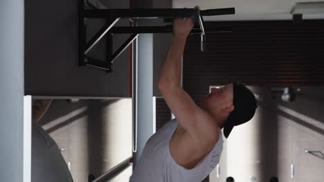 hombre caucásico fuerte y musculoso hace tiradas con peso corporal en el gimnasio cubierto