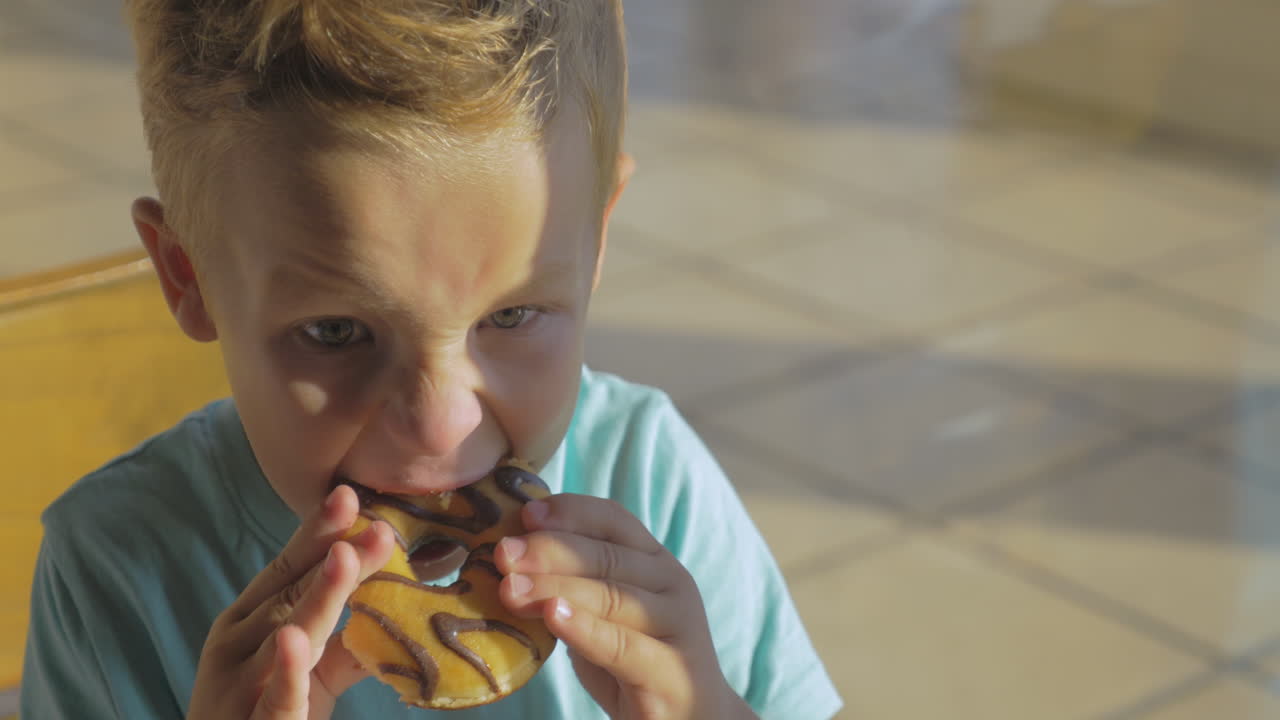 Ragazzo che mangia una ciambella al cioccolato e beve acqua
