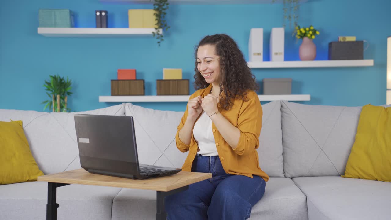mujer joven mirando la computadora portátil aplaudiendo.