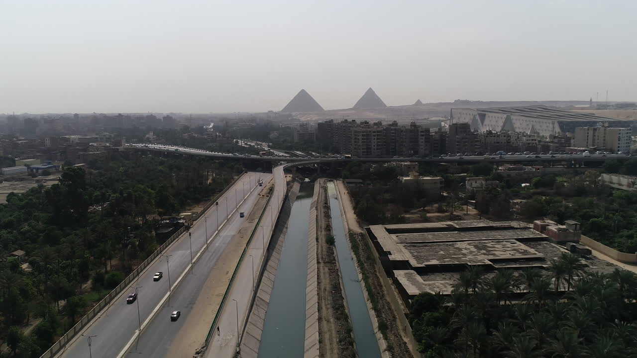 toma aérea de las pirámides de egipto en giza posicionadas en el fondo de una rama del río nilo en el primer plano de la rama de maryotya