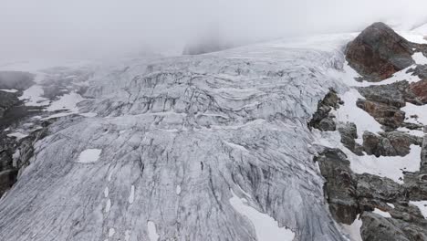 fellaria glacier in valmalenco with rocky mountains shrouded in clouds in background, italy