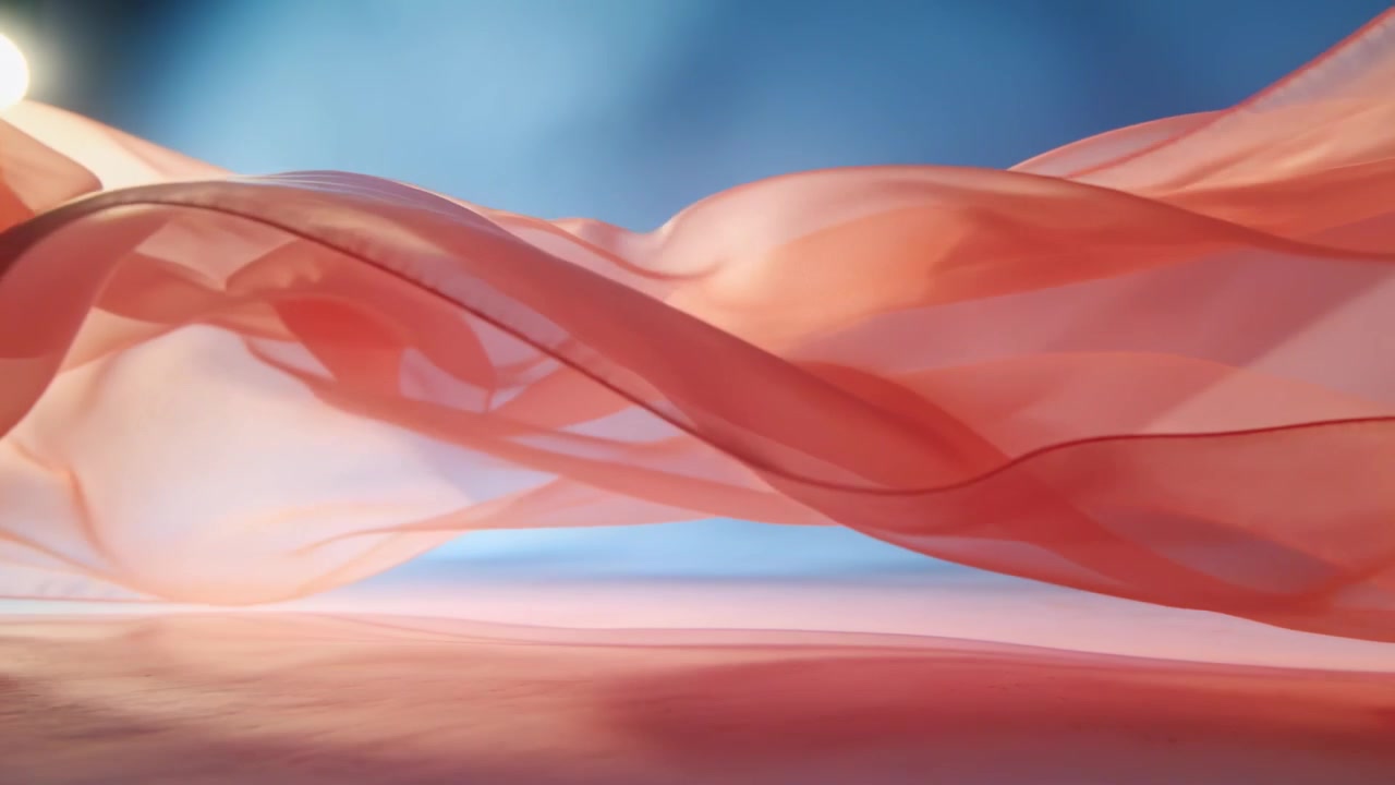 Tessuto velato rosso-rosa che ondeggia, entra da sinistra e si muove sul pavimento spinto dall'aria in studio, con sfondo blu.