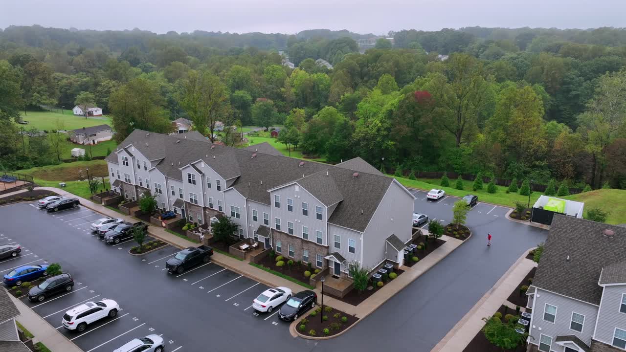 Housing area in American suburb during rainy and foggy day. Neighborhood community in autumn fall. Parking cars on street. Aerial rising reveal shot.