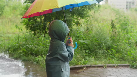 un niño camina bajo la lluvia con un paraguas.