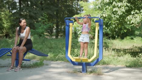 pregnant mother and daughter exercising at outdoor gym