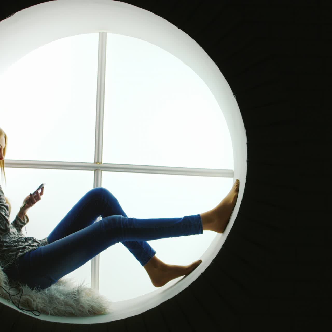 둥근 창문에서 음악을 듣는 여자