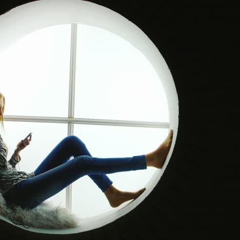 mujer escuchando música en la ventana redonda