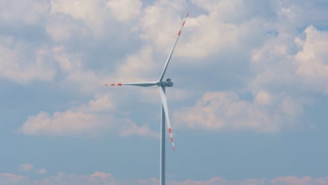 scenic wind turbine generates green energy on a windy day, blue cloudy sky